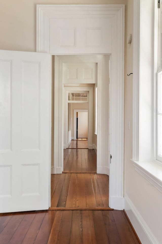corridor featuring baseboards and wood-type flooring