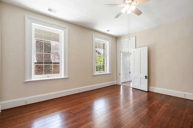 spare room featuring ceiling fan, baseboards, visible vents, and dark wood finished floors