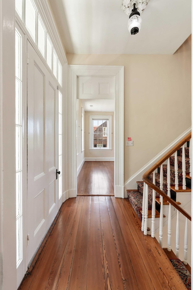foyer entrance with stairway, hardwood / wood-style flooring, and baseboards