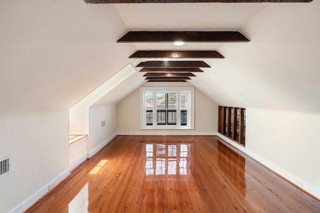 additional living space with light wood finished floors, lofted ceiling with beams, baseboards, and visible vents