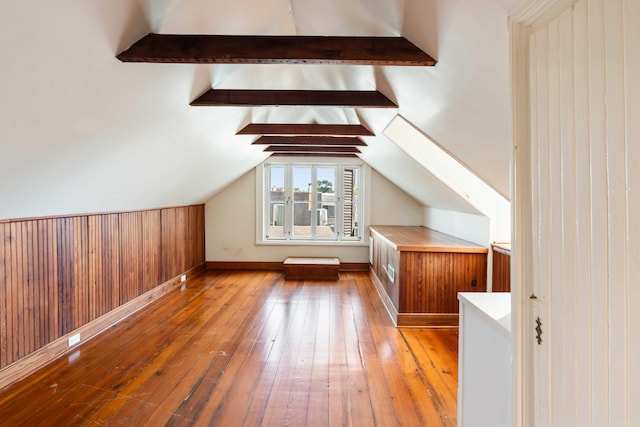 bonus room featuring wood walls, wood-type flooring, and vaulted ceiling with beams