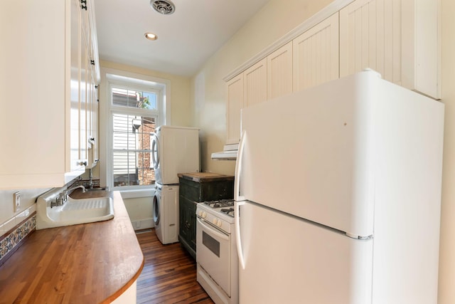 kitchen featuring a sink, white appliances, butcher block counters, stacked washer and dryer, and visible vents