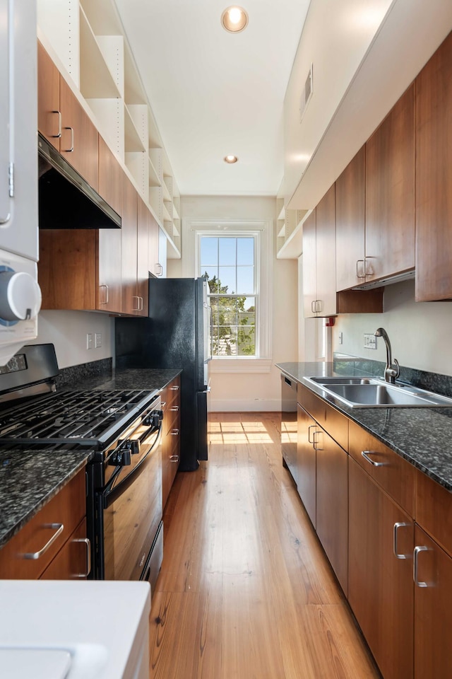 kitchen featuring light wood finished floors, a sink, ventilation hood, visible vents, and appliances with stainless steel finishes
