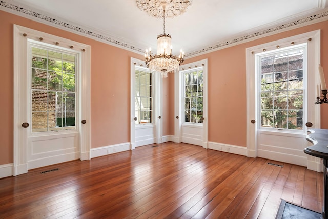 doorway to outside with an inviting chandelier, visible vents, baseboards, and hardwood / wood-style flooring