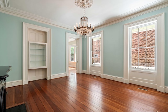 unfurnished dining area with visible vents, a chandelier, crown molding, wood-type flooring, and baseboards