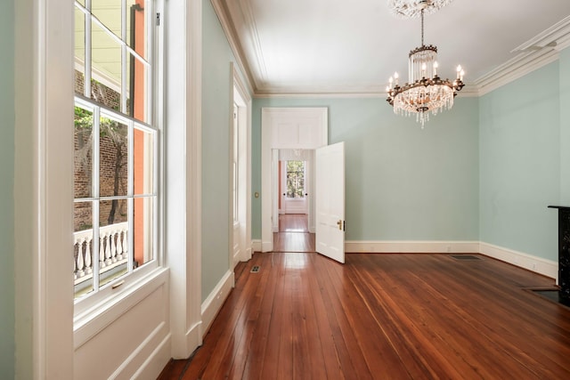 unfurnished dining area with an inviting chandelier, ornamental molding, baseboards, and hardwood / wood-style floors