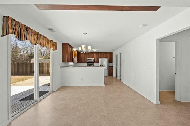 kitchen with a chandelier, stainless steel appliances, decorative light fixtures, and kitchen peninsula