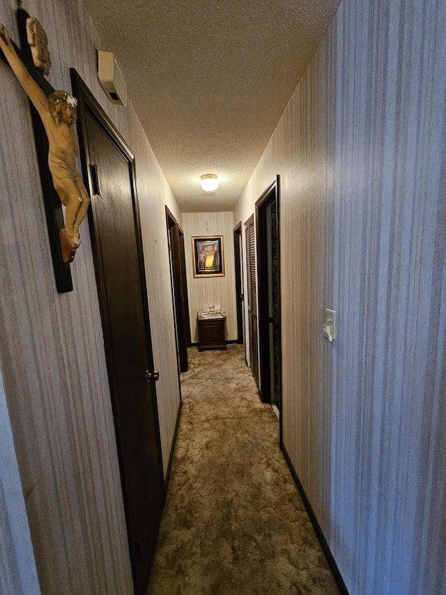 hallway with light carpet and a textured ceiling