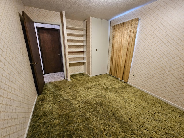 unfurnished bedroom with a textured ceiling, multiple closets, carpet flooring, and wallpapered walls