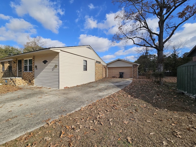 view of property exterior featuring an outbuilding, brick siding, and a detached garage