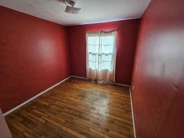 empty room with dark wood-type flooring and baseboards