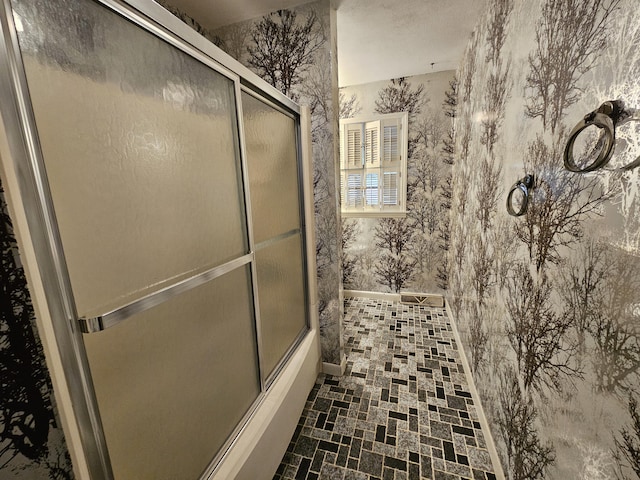 bathroom with baseboards, combined bath / shower with glass door, and wallpapered walls