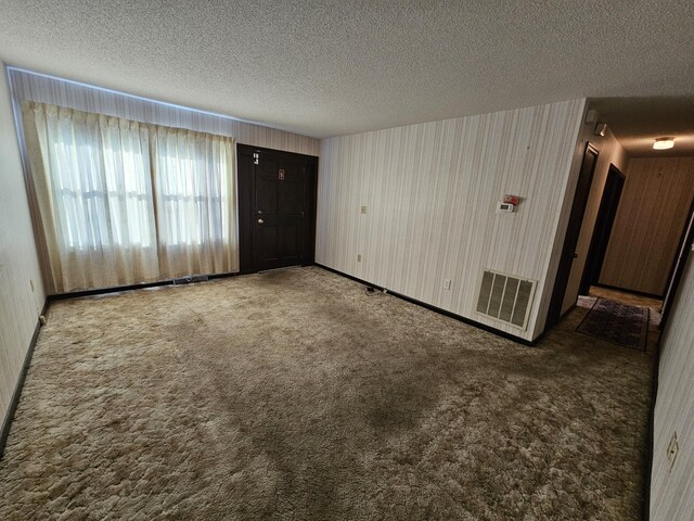 spare room with a textured ceiling, carpet, and visible vents