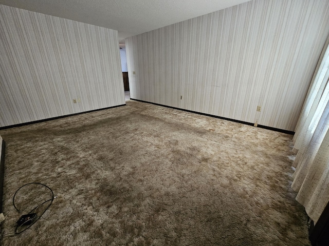 unfurnished bedroom with carpet, a textured ceiling, baseboards, and wallpapered walls