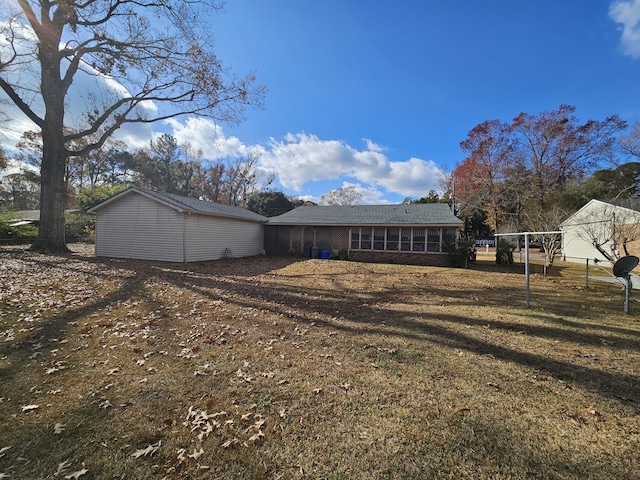 back of property with brick siding, a sunroom, and a yard