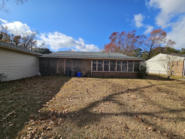 back of property with a sunroom, brick siding, fence, and a lawn