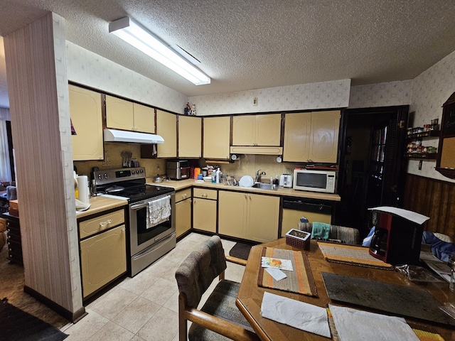 kitchen featuring white appliances, under cabinet range hood, light countertops, and wallpapered walls