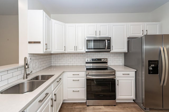 kitchen featuring stainless steel appliances, a sink, white cabinetry, and light countertops