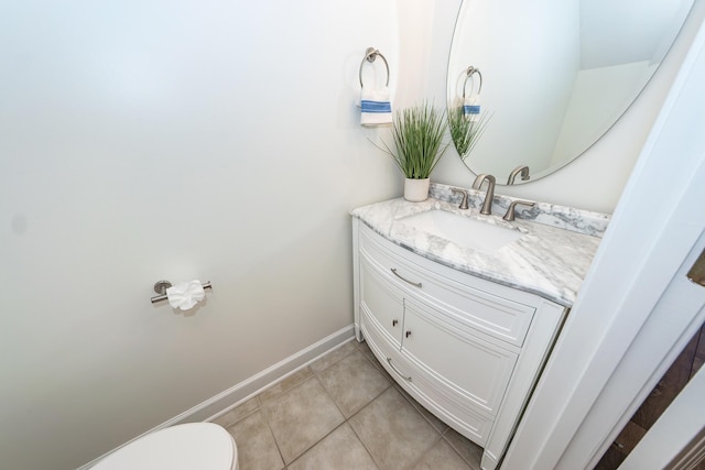 half bath with vanity, tile patterned floors, toilet, and baseboards