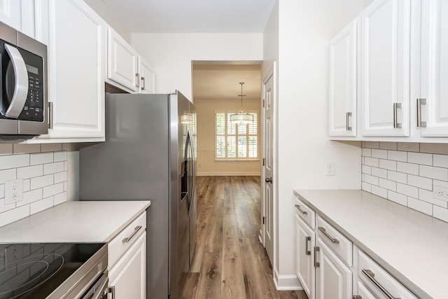 kitchen with stainless steel appliances, wood finished floors, white cabinets, and light countertops