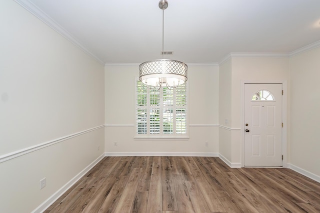 unfurnished dining area featuring ornamental molding, wood finished floors, baseboards, and a chandelier