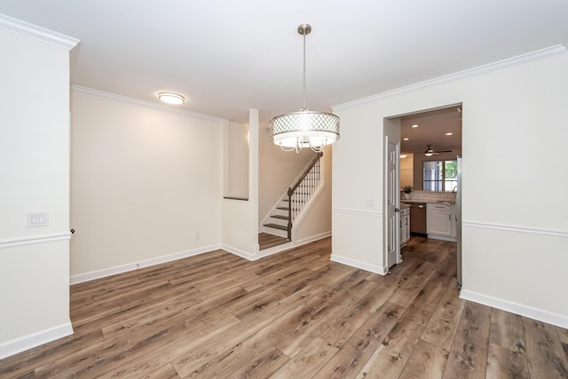 unfurnished dining area with ornamental molding, stairway, wood finished floors, baseboards, and a ceiling fan