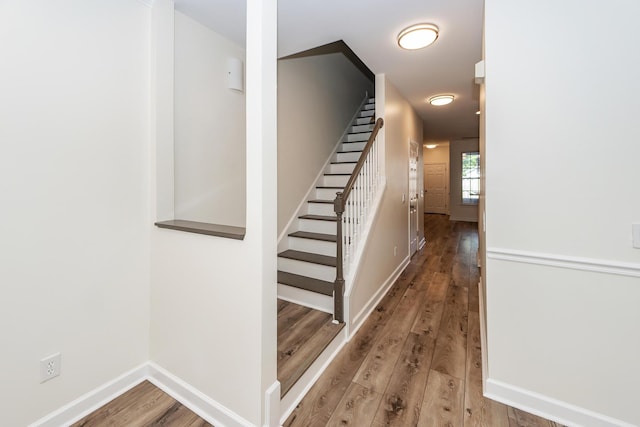 staircase featuring wood finished floors and baseboards