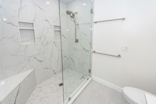 bathroom with a marble finish shower, toilet, and baseboards