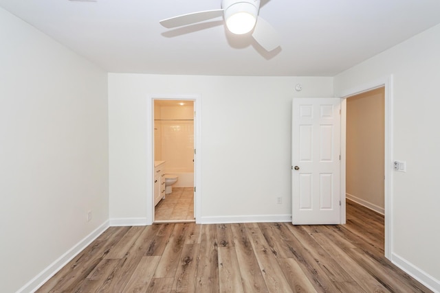 unfurnished bedroom with light wood-type flooring, baseboards, connected bathroom, and a ceiling fan
