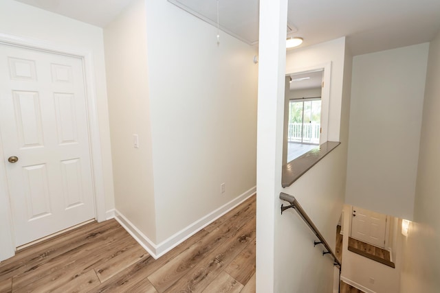 hallway with an upstairs landing, attic access, light wood-type flooring, and baseboards