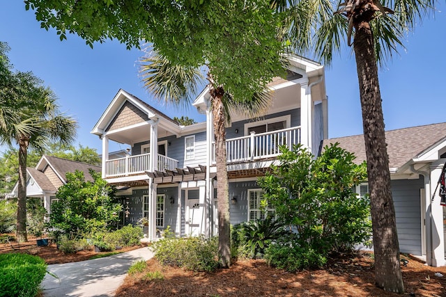 view of front of house featuring a balcony and a shingled roof