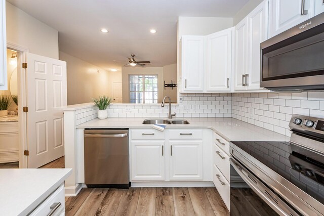 kitchen with stainless steel appliances, a sink, a ceiling fan, white cabinets, and decorative backsplash