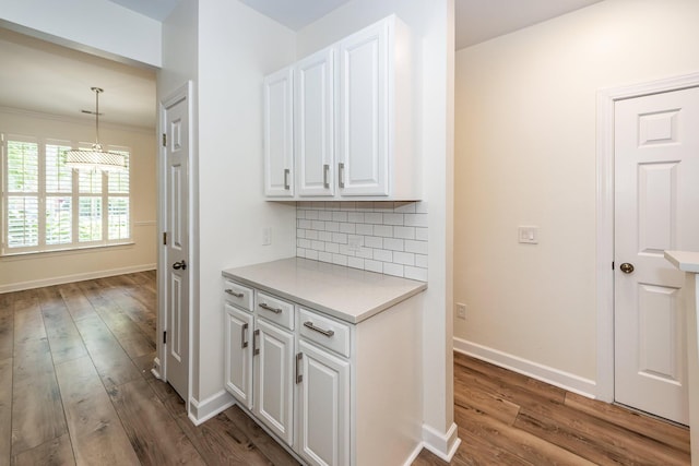 corridor with wood finished floors, baseboards, and crown molding
