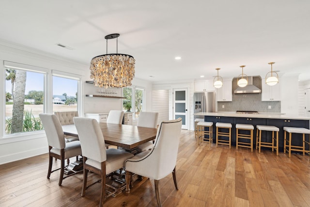 dining space featuring crown molding, an inviting chandelier, and light wood-type flooring