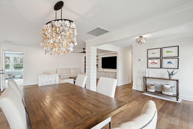 dining room featuring ornamental molding, a chandelier, hardwood / wood-style floors, and ornate columns