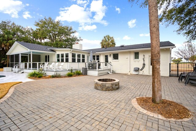 back of house with a fire pit, a sunroom, a patio, and a deck