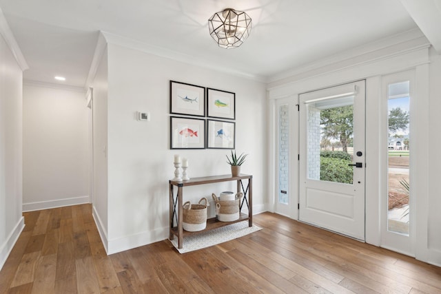 entryway with ornamental molding and hardwood / wood-style floors