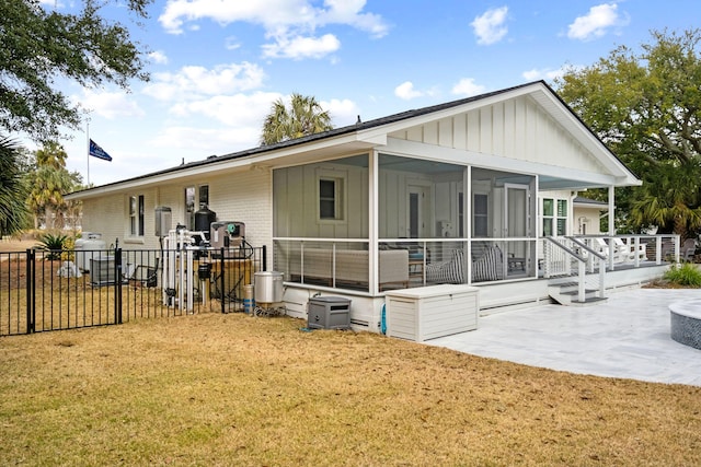 rear view of house featuring a patio, a sunroom, and a lawn