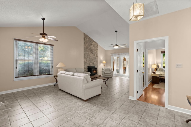 living room with a wood stove, ceiling fan, a healthy amount of sunlight, and vaulted ceiling