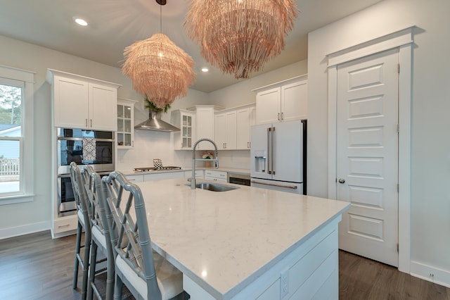 kitchen with stainless steel appliances, white cabinetry, a kitchen island with sink, and sink