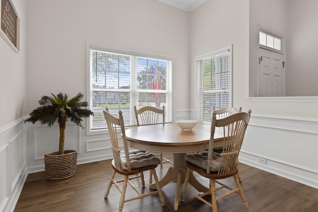 dining space featuring wainscoting, ornamental molding, a decorative wall, and wood finished floors