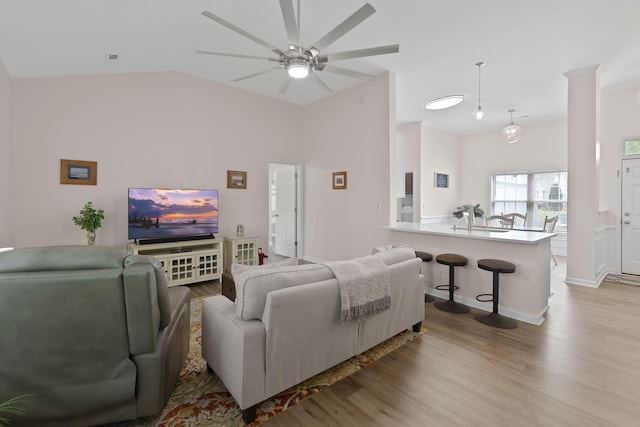 living area featuring baseboards, ceiling fan, wood finished floors, and lofted ceiling
