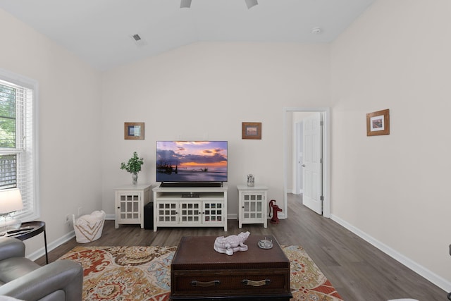 living area with baseboards, a ceiling fan, wood finished floors, and vaulted ceiling