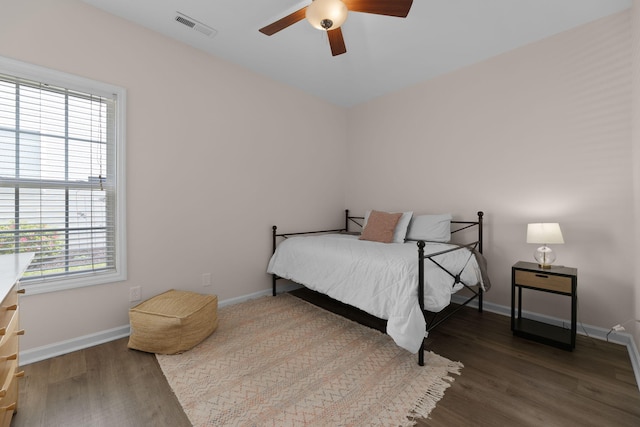 bedroom with baseboards, ceiling fan, wood finished floors, and visible vents