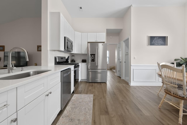 kitchen featuring light wood-type flooring, light countertops, white cabinets, a sink, and appliances with stainless steel finishes