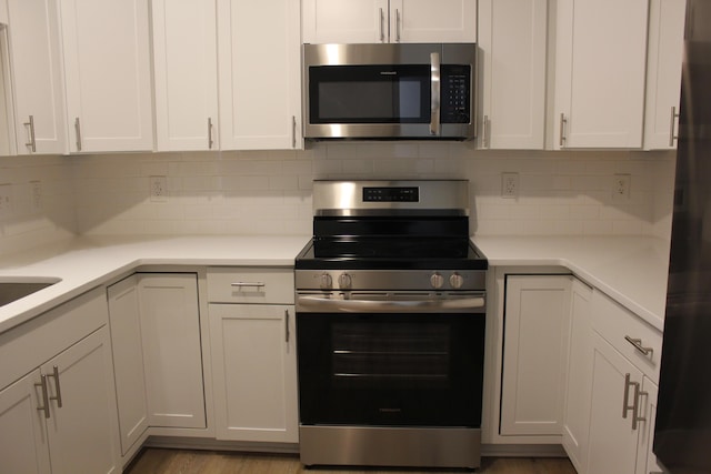 kitchen featuring decorative backsplash, white cabinetry, and appliances with stainless steel finishes