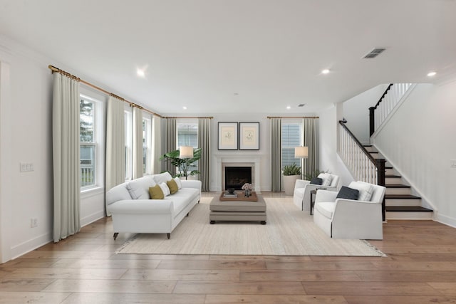 living area with stairway, a fireplace, visible vents, and wood-type flooring