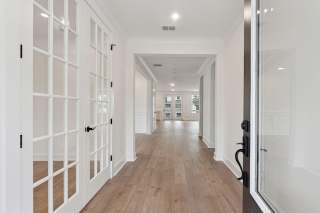 hallway with light wood-type flooring, french doors, baseboards, and ornamental molding