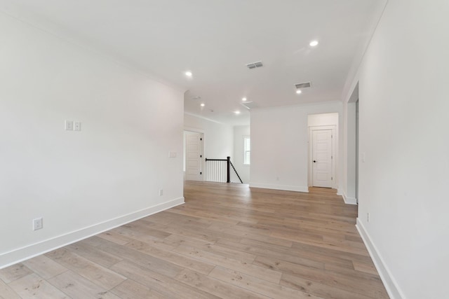 unfurnished room featuring visible vents, light wood-style flooring, baseboards, and ornamental molding