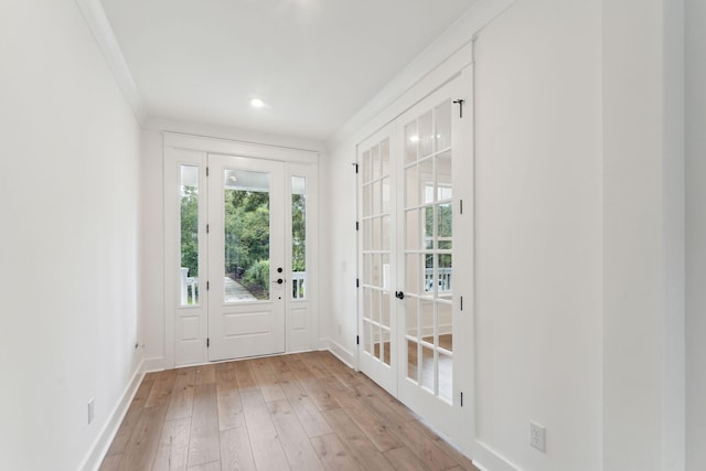 doorway to outside featuring baseboards, light wood-type flooring, and ornamental molding